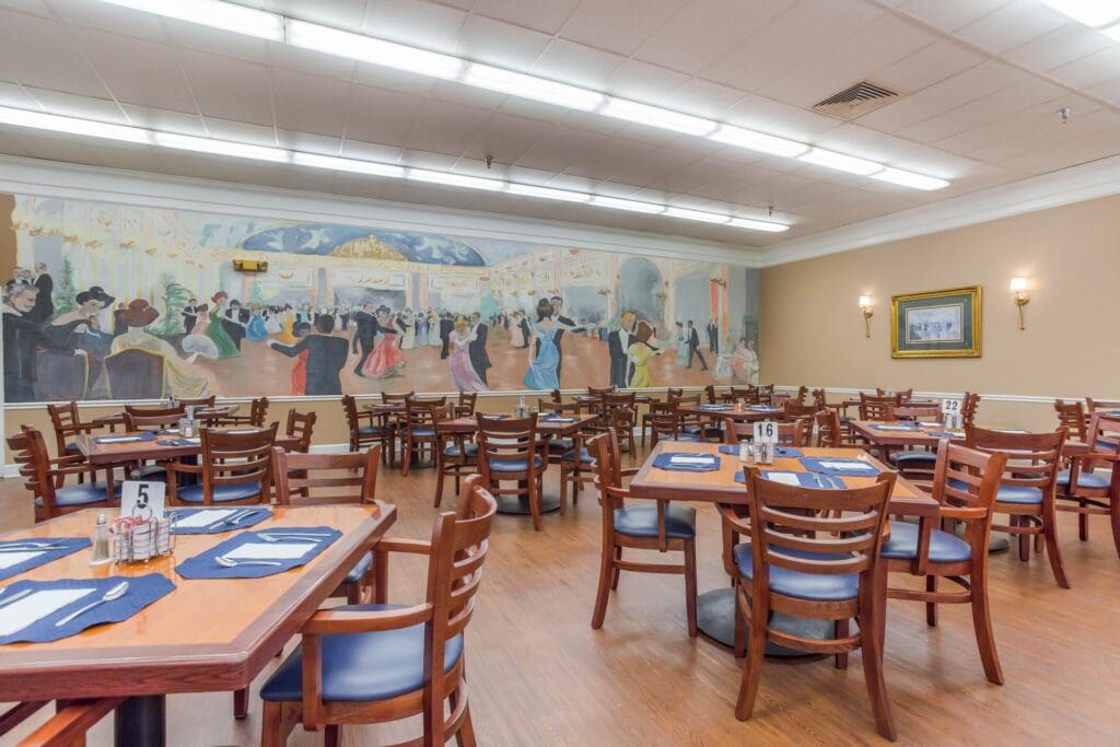 Large dining room filled with tables and chairs featuring a mural of ballroom dancers on the wall