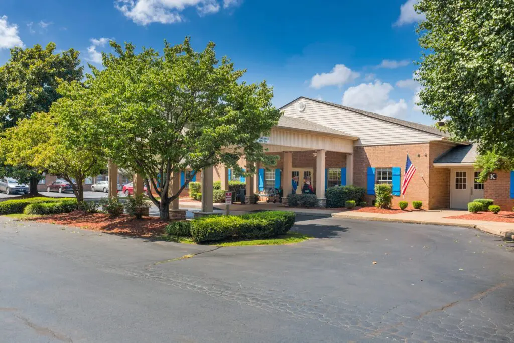 Exterior of main lobby with entrance covered by large canopy and surrounded by trees and landscaping