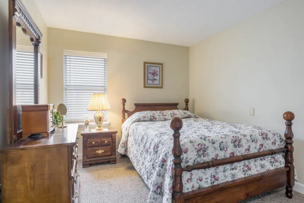 Bedroom with bed, sidetable, dresser, window, lamp, and painting